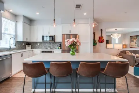 a kitchen with kitchen island a dining table chairs stainless steel appliances and cabinets