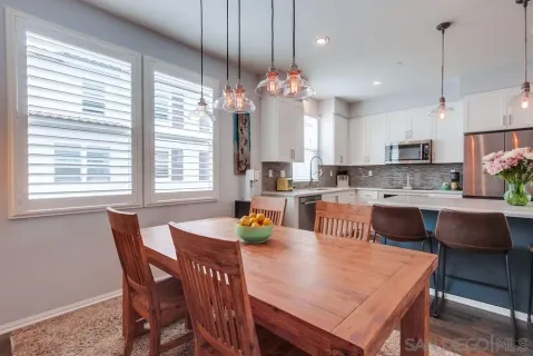 a kitchen with stainless steel appliances granite countertop a dining table chairs refrigerator and microwave