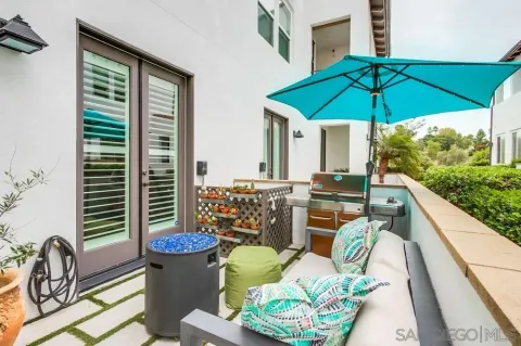 a view of a patio with couches table and chairs under an umbrella