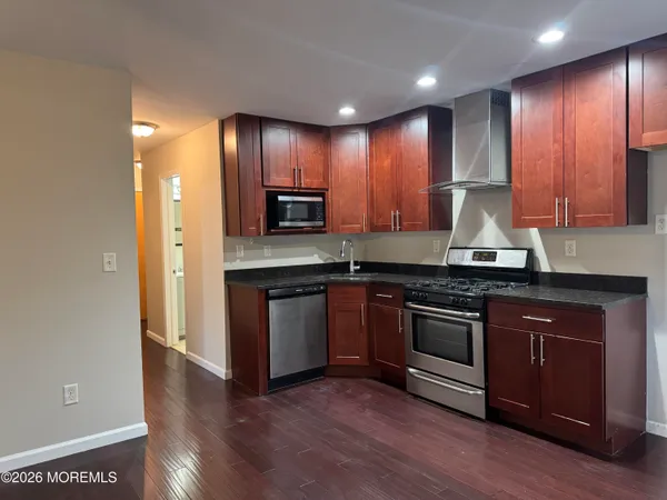 a kitchen with stainless steel appliances granite countertop wooden cabinets a stove a sink and a microwave