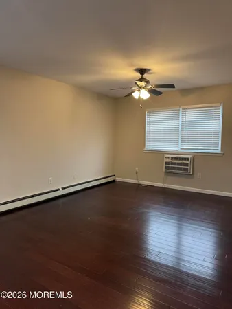 a view of an empty room with a window and wooden floor