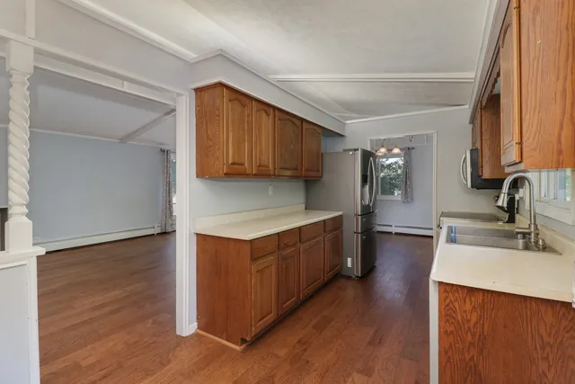a kitchen with stainless steel appliances granite countertop wooden cabinets a sink and a hard wood floor