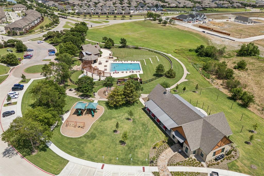 1014 Dunhill Lane Forney, TX 75126 - Photo 32 of 38 Aerial perspective showcasing a community amenity center with a rectangular swimming pool, nearby shaded structures, and a playground area with swings and slides