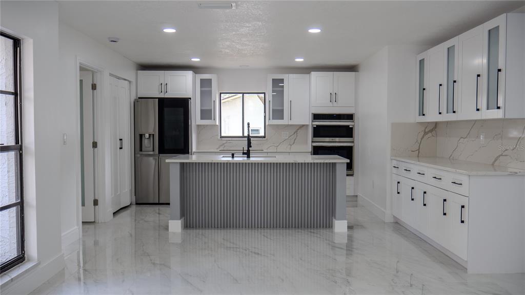 7984 Floral Drive Weeki Wachee, FL 34607 - Photo 5 of 31 a kitchen with granite countertop a refrigerator and a stove top oven