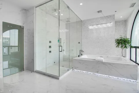 a bathroom with a tub a sink a mirror and a shower