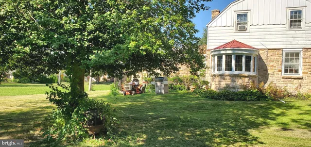a view of a white house next to a yard with big trees
