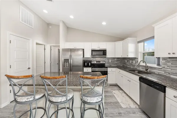 a kitchen with stainless steel appliances kitchen island granite countertop a sink and cabinets