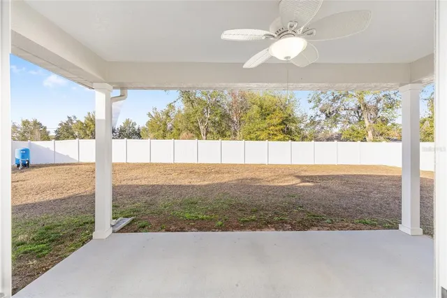 an empty room with large windows and ceiling fan