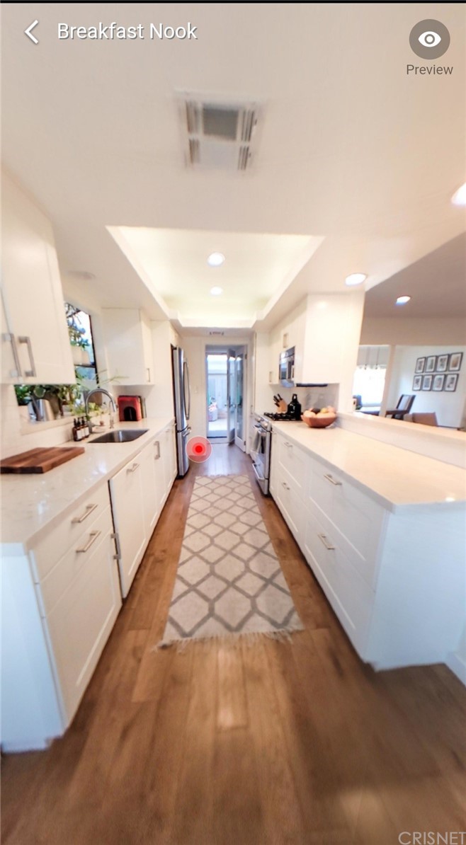 14721 Weddington Street Sherman Oaks, CA 91411 - Photo 10 of 17 a large white room with kitchen island a stove a sink dishwasher and white cabinets with wooden floor