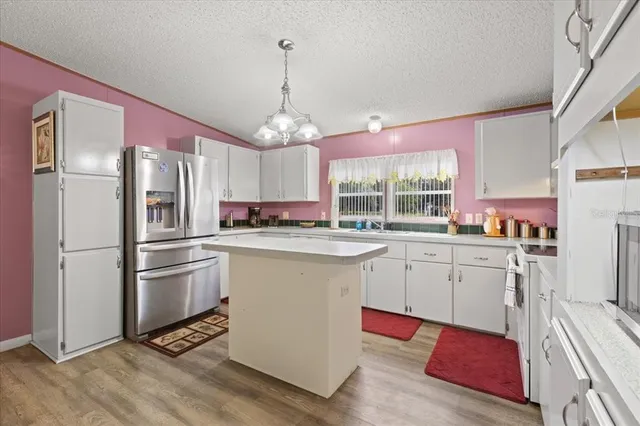 a kitchen with granite countertop stainless steel appliances a center island cabinets and a window