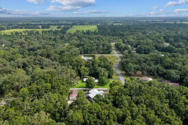 an aerial view of residential house with outdoor space and trees all around