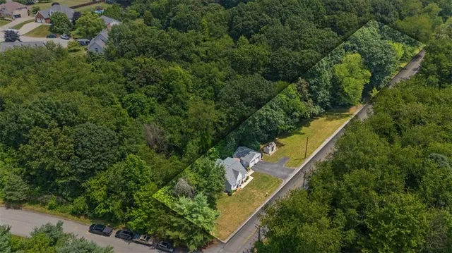 an aerial view of residential house with outdoor space and trees all around