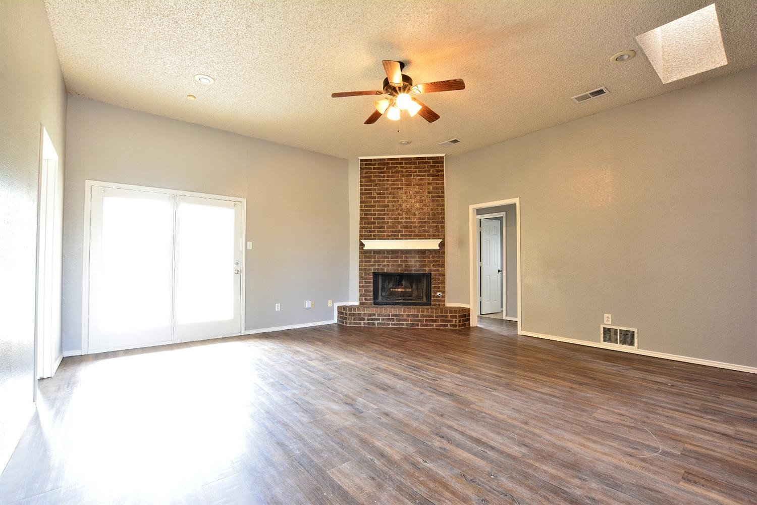 5917 71st Street Lubbock, TX 79424 - Photo 7 of 18 an empty room with wooden floor fireplace and fan