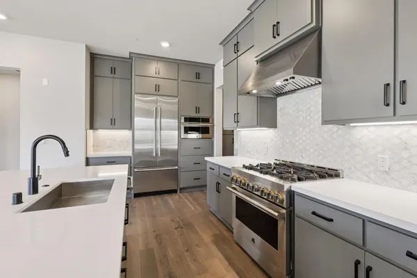 a kitchen with stainless steel appliances granite countertop a stove a sink and a refrigerator