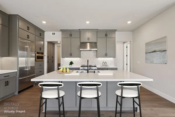a kitchen with stainless steel appliances kitchen island granite countertop a dining table chairs and refrigerator
