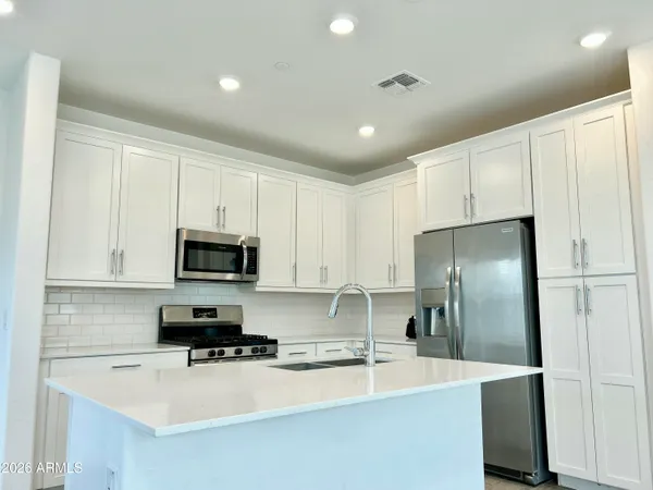 a kitchen with kitchen island a refrigerator sink and white cabinets