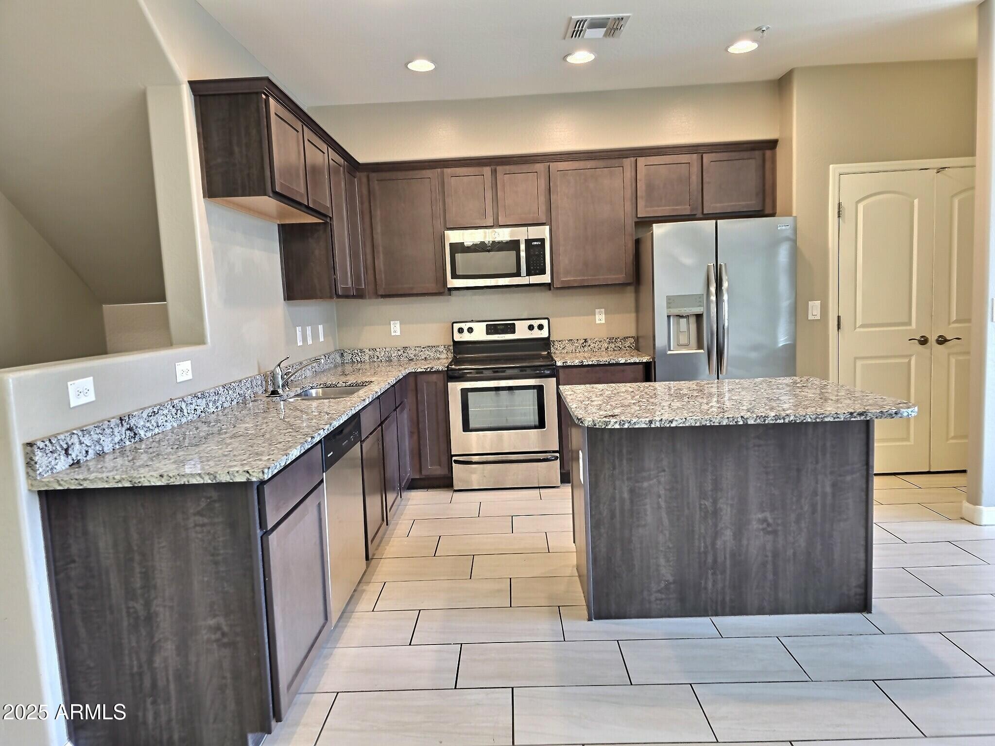 240 West Juniper Avenue, Unit 1111 Gilbert, AZ 85233 - Photo 6 of 22 a kitchen with kitchen island granite countertop a sink stove and refrigerator