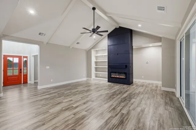 an empty room with wooden floor fireplace and windows