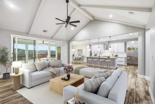 a living room with furniture kitchen view and a large window