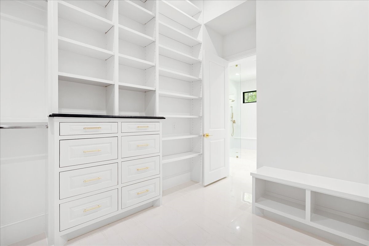 26041 Crown Ranch Boulevard Montgomery, TX 77316 - Photo 39 of 45 An expansive primary closet with approximately eleven-foot ceilings, built-in drawers, shelving, and floor-to-ceiling storage brings boutique-style organization into everyday life.