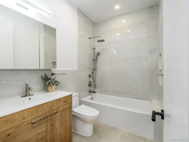 a bathroom with a bathtub shower sink vanity mirror and toilet