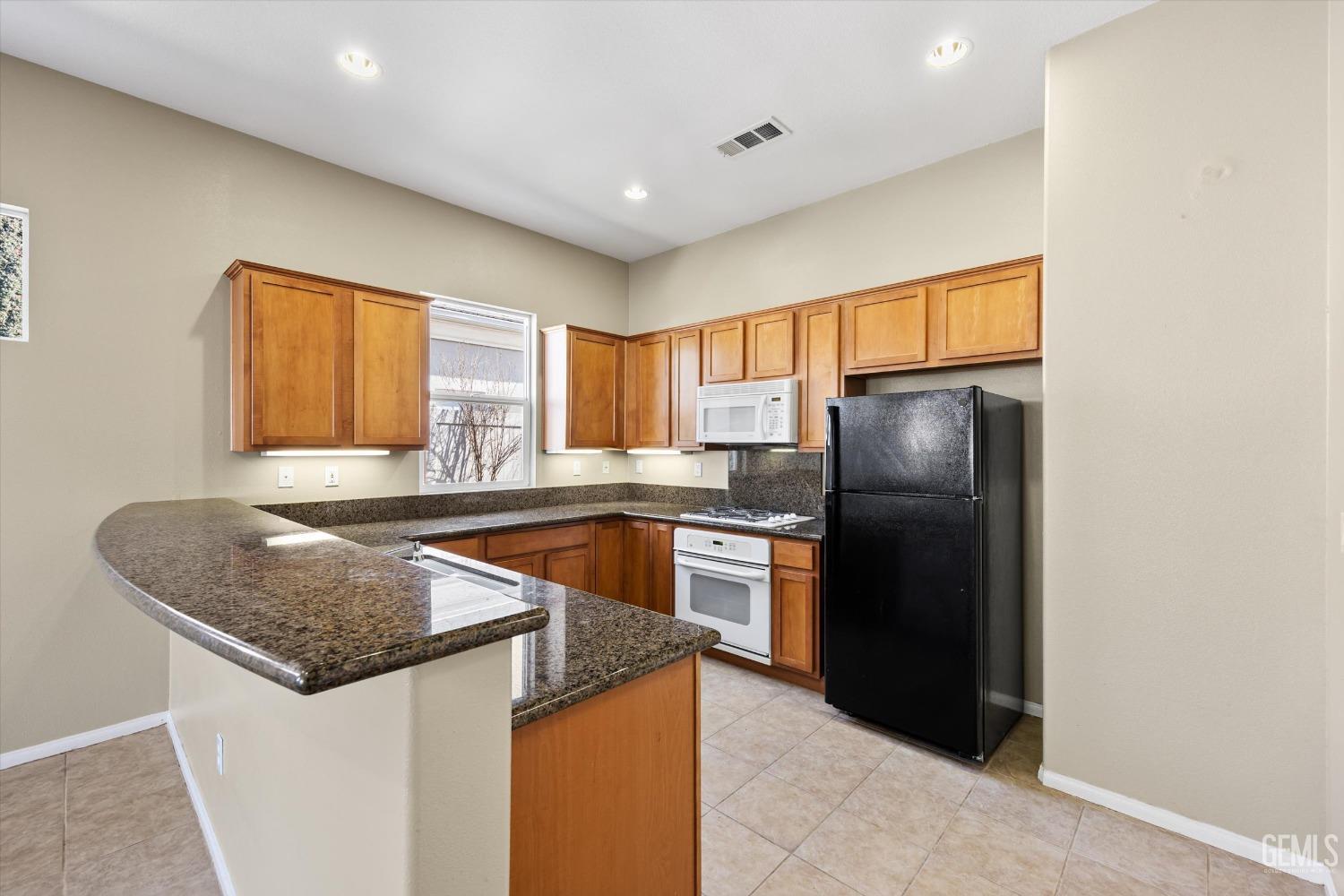 Undisclosed Address Bakersfield, CA 93306 - Photo 15 of 35 a kitchen with granite countertop a refrigerator and a sink