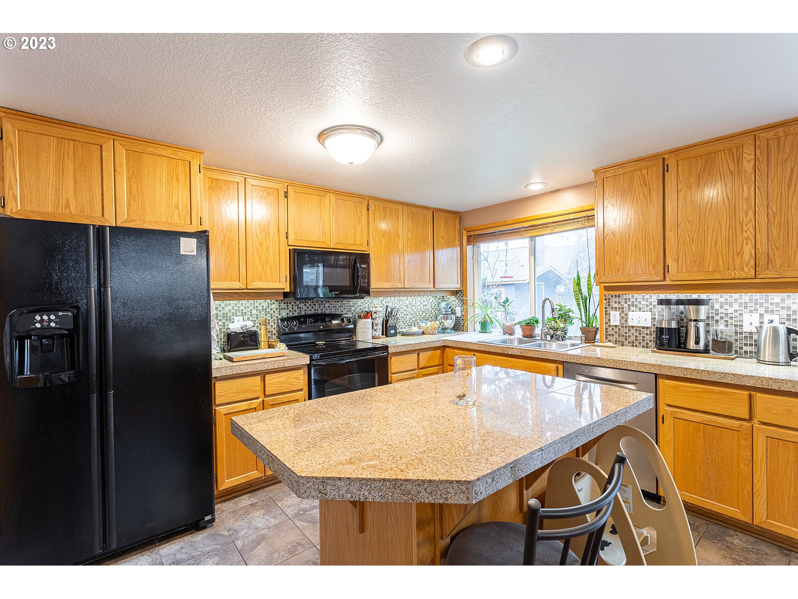 4010 Torrington Avenue Eugene, OR 97404 - Photo 10 of 35 a kitchen with stainless steel appliances granite countertop a refrigerator a sink dishwasher and wooden cabinets with a large window
