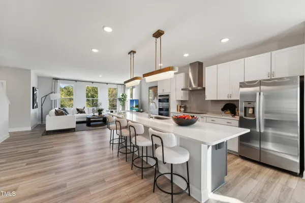 a kitchen with stainless steel appliances a dining table chairs stove and refrigerator