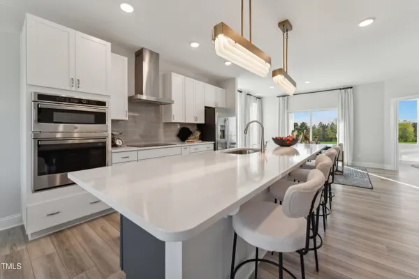 a kitchen with stainless steel appliances kitchen island a table chairs in it and wooden floors