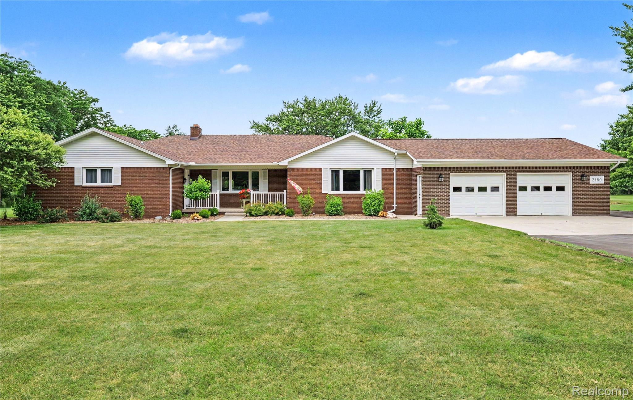 Brick exterior with white siding accents and a brown shingle roof