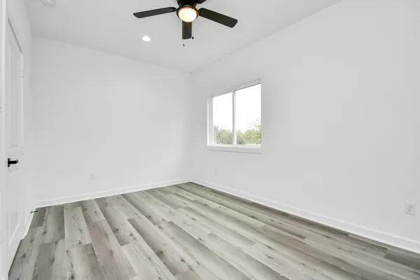 an empty room with a window and ceiling fan