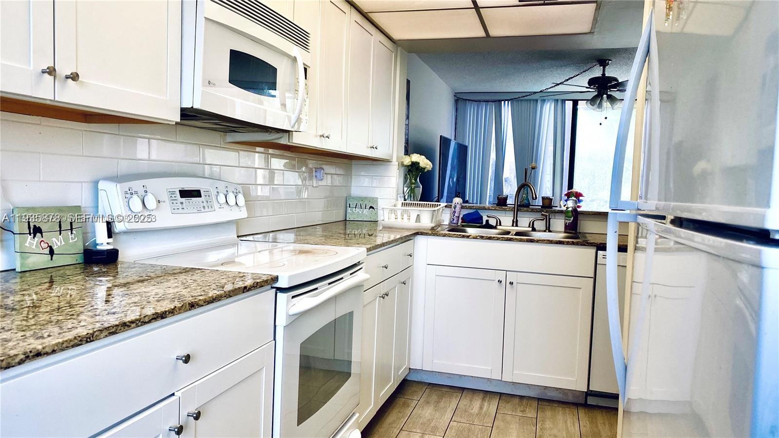 2931 Southwest 87th Terrace, Unit 1923 Davie, FL 33328 - Photo 4 of 15 a kitchen with granite countertop cabinets stainless steel appliances a sink and wooden floor