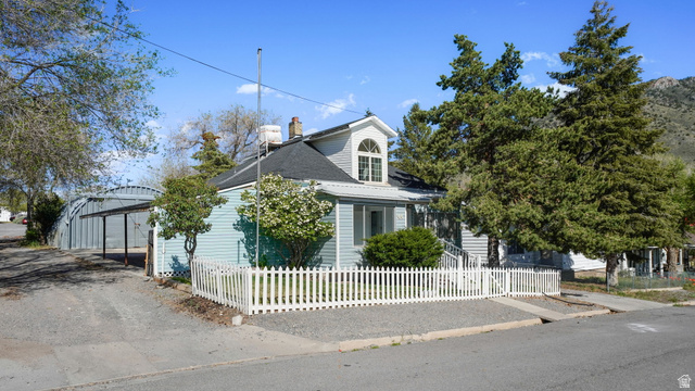 44 Shriver Street Eureka, UT 84628 - Photo 26 of 43 Light blue siding exterior with a white picket fence, featuring a prominent dormer window