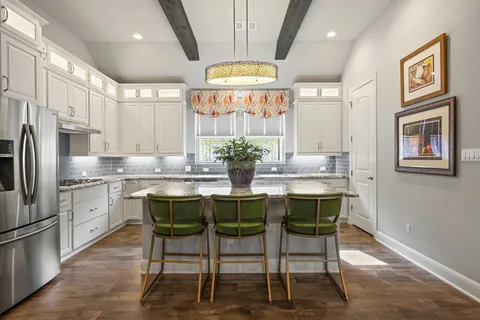 a kitchen with stainless steel appliances granite countertop a stove a refrigerator and a dining table with wooden floor