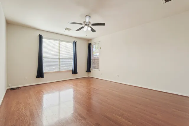 a view of an empty room with wooden floor and a window