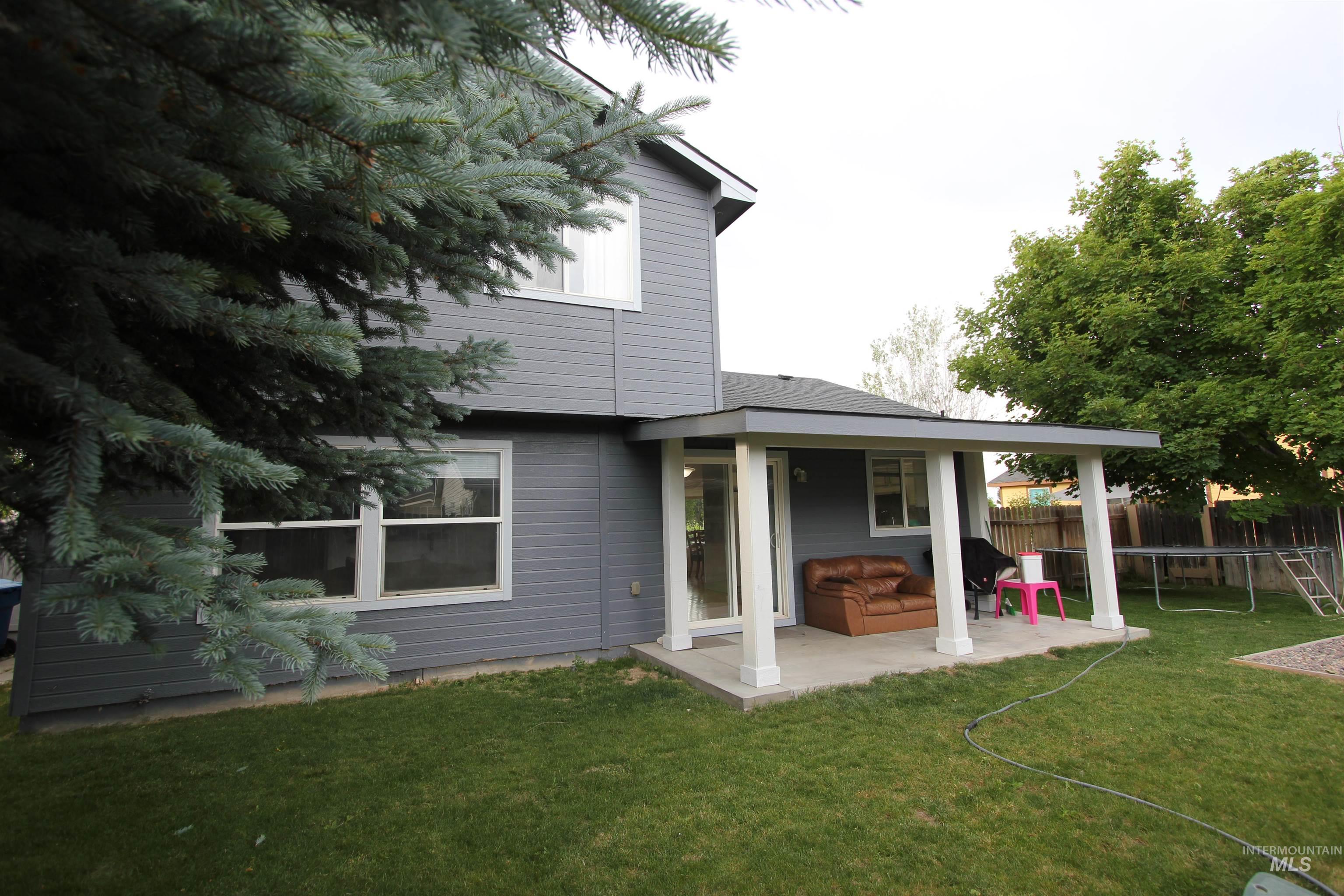 4816 Kadie Street Caldwell, ID 83607 - Photo 22 of 23 Rear exterior featuring a covered patio with white columns, a sliding glass door, and a manicured lawn