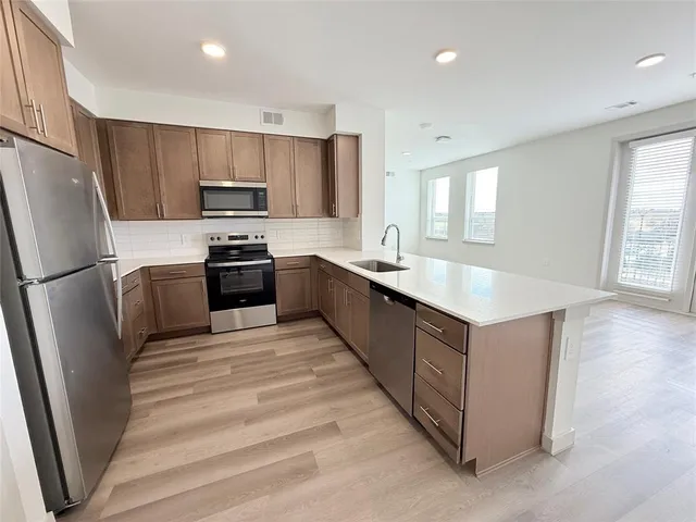 a kitchen with stainless steel appliances granite countertop a refrigerator a sink a stove a microwave and island