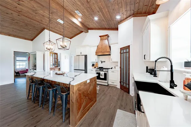 a kitchen with stainless steel appliances kitchen island granite countertop a table chairs in it and wooden floors