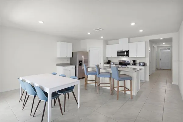 a kitchen with stainless steel appliances kitchen island granite countertop a dining table chairs and sink