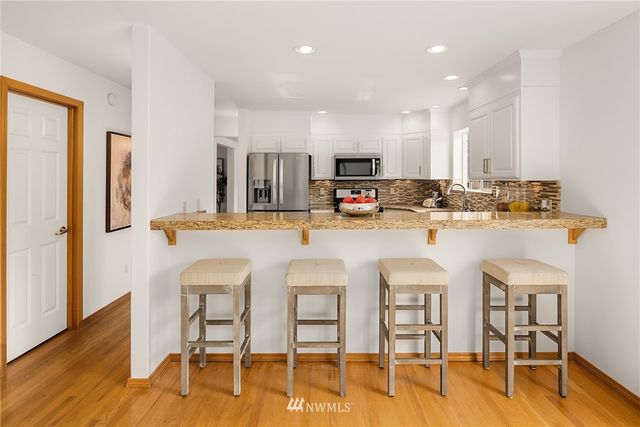 a kitchen with stainless steel appliances a dining table chairs refrigerator and sink