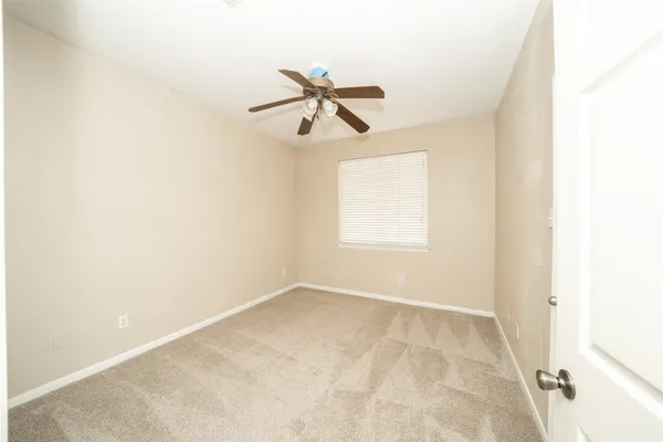 an empty room with windows and fan