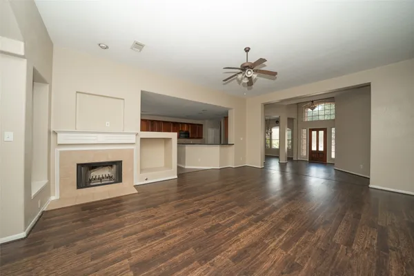 an empty room with wooden floor fireplace and windows