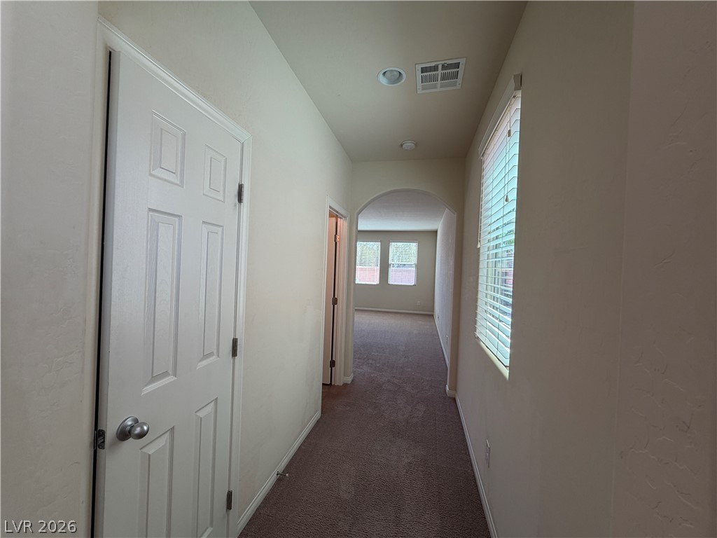 442 White Heart Road Las Vegas, NV 89148 - Photo 3 of 25 An arched doorway highlights the transition through this carpeted hallway featuring recessed lighting.