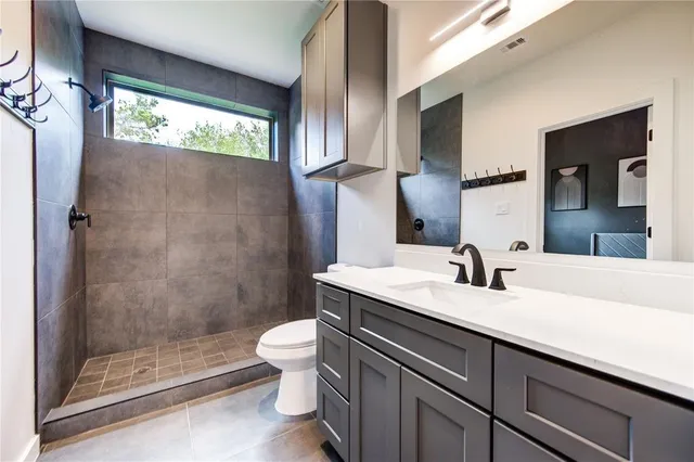 a bathroom with a granite countertop sink a toilet a mirror and shower