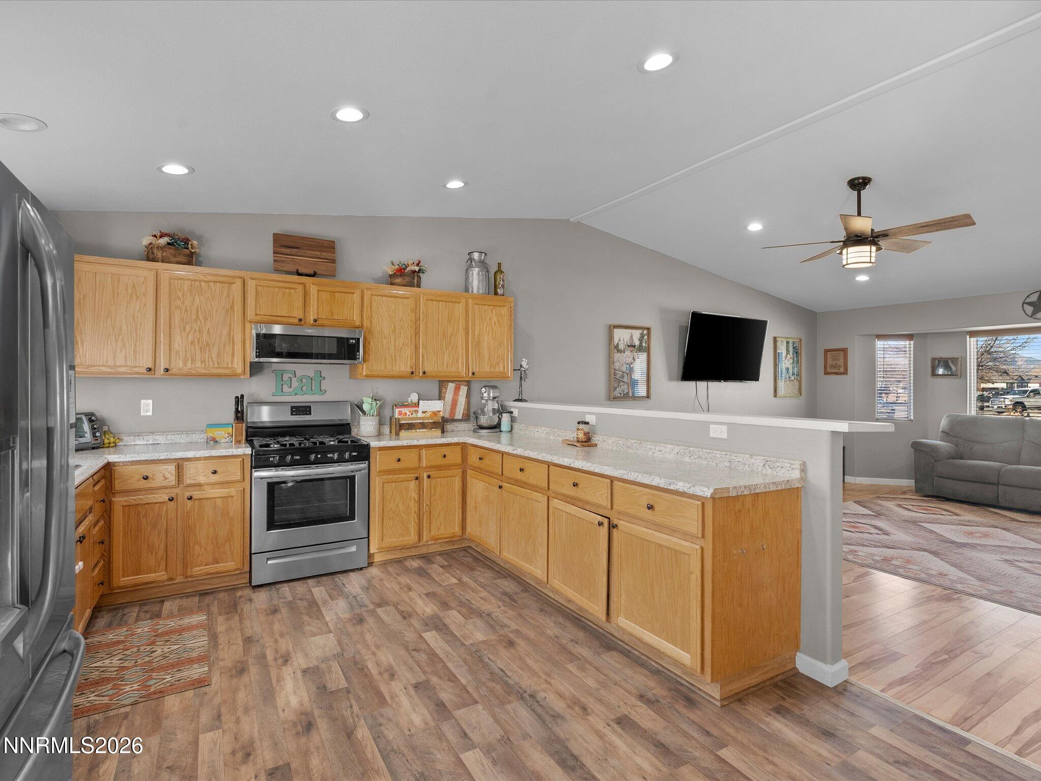 668 Farm Circle Fernley, NV 89408 - Photo 16 of 46 a kitchen with stainless steel appliances granite countertop a stove top oven a sink a refrigerator and white cabinets with wooden floor