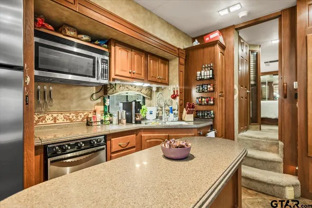 a dining hall with stainless steel appliances kitchen island granite countertop a sink and cabinets