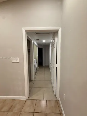 a view of an empty room with chandelier fan and windows