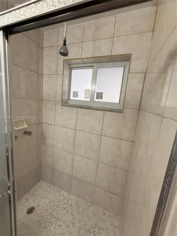 a bathroom with a granite countertop sink a mirror and shower