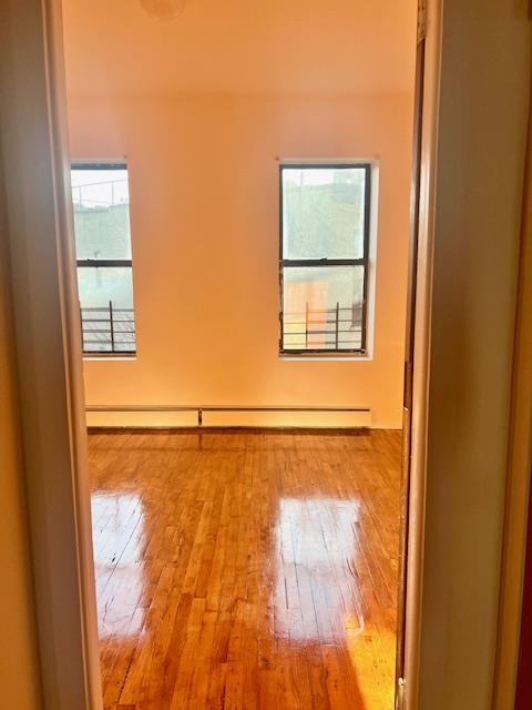 Empty room with light hardwood / wood-style floors, a wealth of natural light, and a baseboard radiator