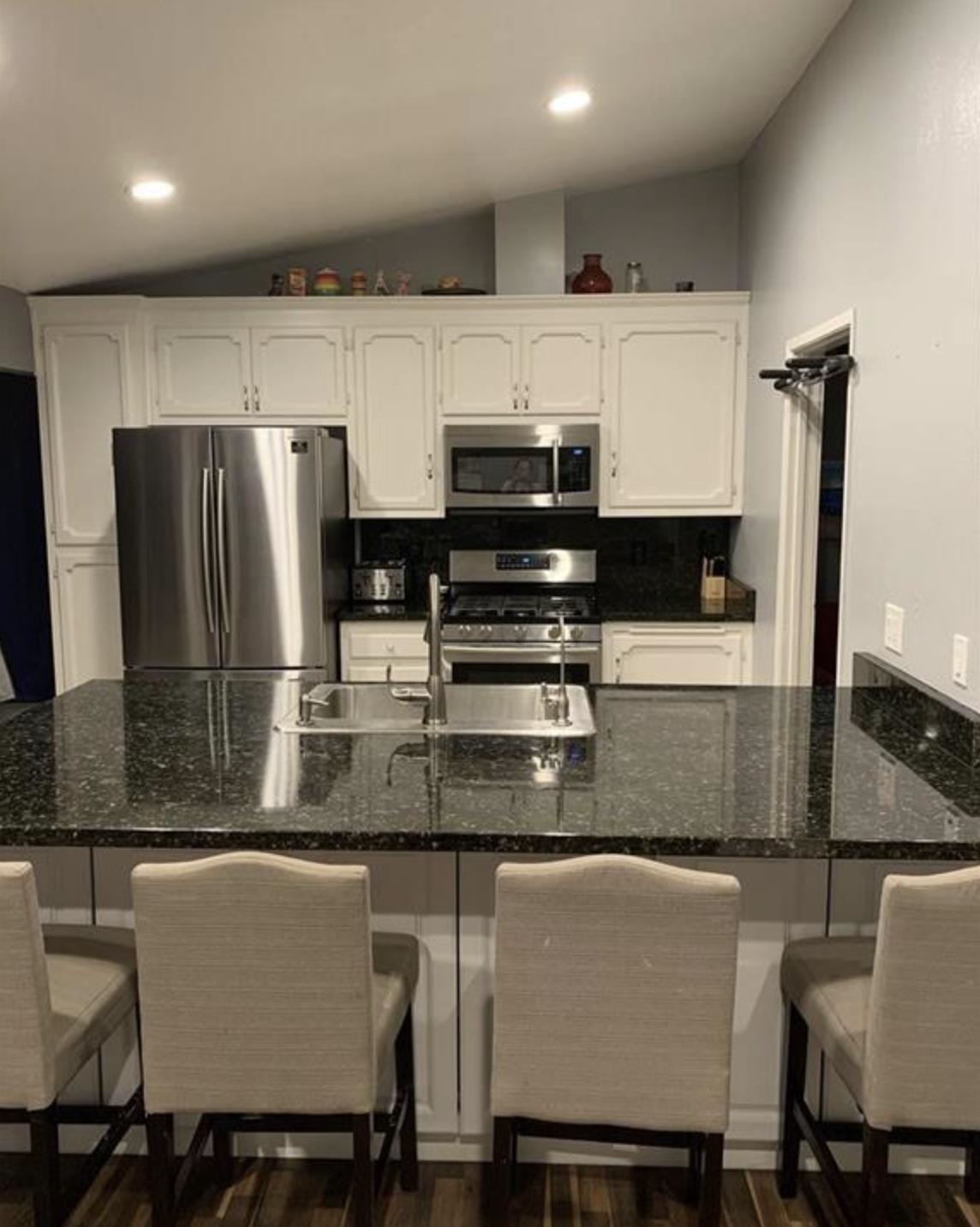 5250 Riverlake Road Discovery Bay, CA 94505 - Photo 2 of 18 Kitchen featuring vaulted ceiling, a kitchen bar, stainless steel appliances, white cabinets, and a peninsula